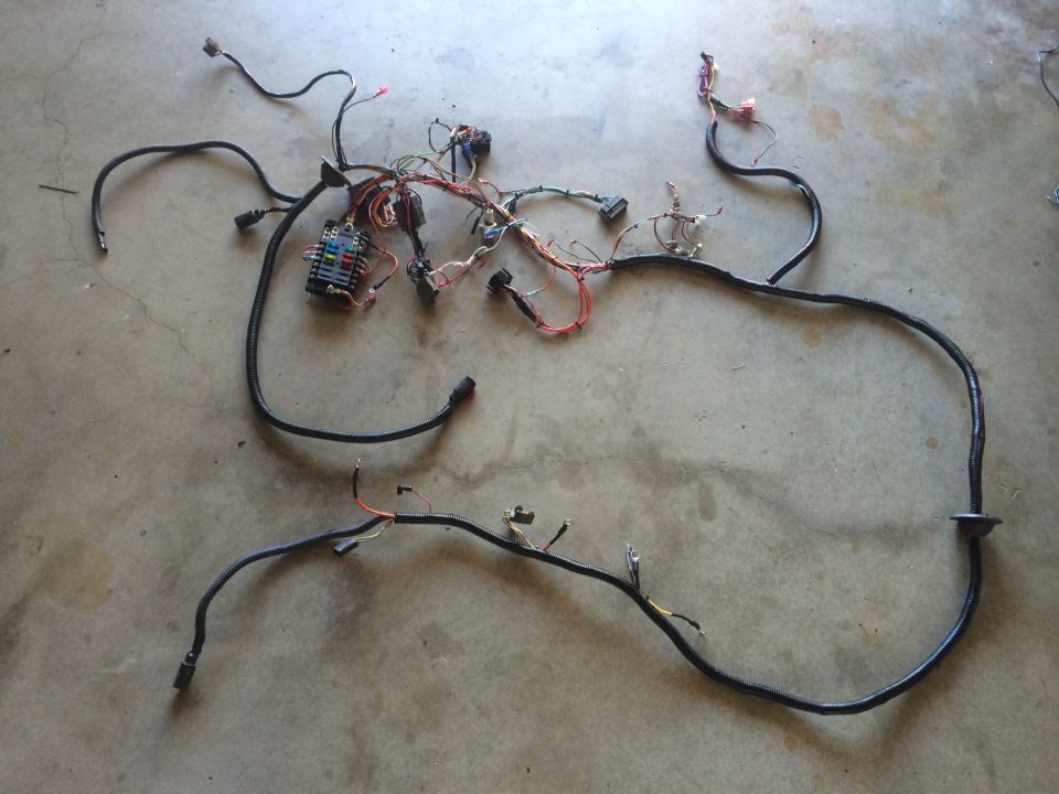 Vehicle wiring harness laid out on concrete floor. Includes fuse box and various connectors