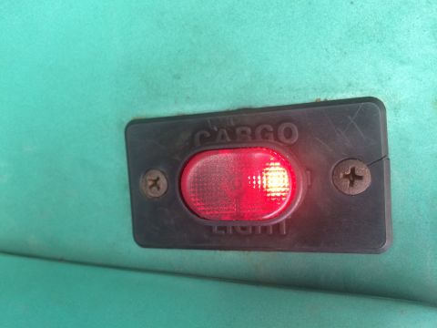 1977 Ford F-350 - A close-up view of a red illuminated cargo light switch, indicating its operational status.
