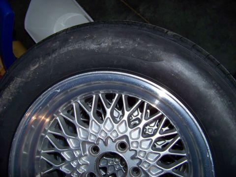 1999 Mercury Grand Marquis - A close-up view of a wire wheel and tire, with the Supermotors.net logo in the lower right corner.
