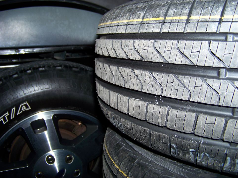 Stack of tires, one with a silver rim and BFGoodrich branding, in a dark space