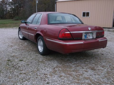 1999 Mercury Grand Marquis - Rear view of a 1999 Mercury Grand Marquis with aftermarket wheels parked on a gravel lot.