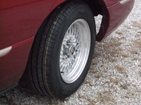 1999 Mercury Grand Marquis - Aftermarket mesh wheel installed on a red vehicle.
