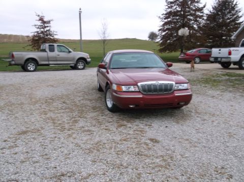 1999 Mercury Grand Marquis - Front view of a 1999 Mercury Grand Marquis parked on a gravel lot with other vehicles present.