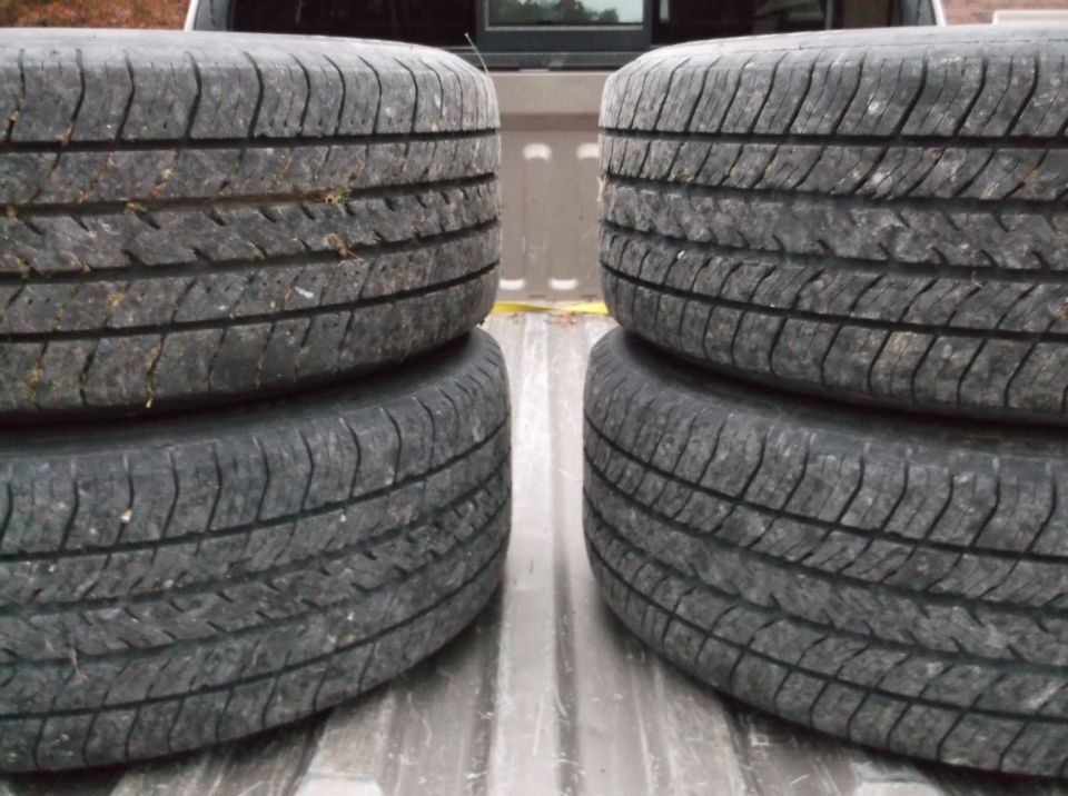 Four tires stacked in the bed of a pickup truck