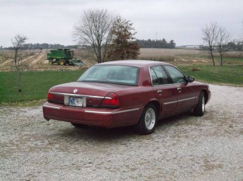 1999 Mercury Grand Marquis - Maroon 1999 Mercury Grand Marquis parked on gravel with a combine in the background.