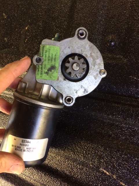 1990 Ford F-150 - A power window motor assembly with a visible gear and a label indicating it was made in India.