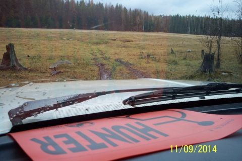 1990 Ford Bronco - Dashboard view from a vehicle driving through a muddy, wooded area. A red 'HUNTER' sign is visible.