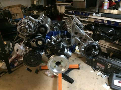 1996 Ford Bronco - A V8 engine is mounted on an orange stand in a garage setting, with various engine components visible.