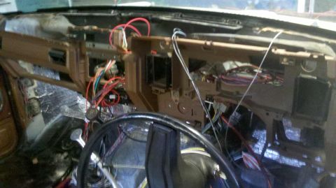 1982 Ford Bronco - The dashboard of a vehicle is disassembled, revealing a complex network of wires and insulation.