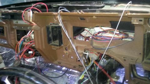 1982 Ford Bronco - The dashboard of a vehicle is disassembled, revealing a complex network of wires and insulation.