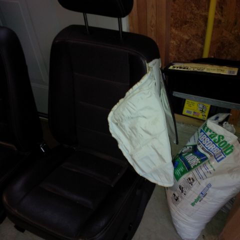 1978 Ford Bronco - A car seat with its airbag deployed sits next to a bag of absorbent material in what appears to be a garage.