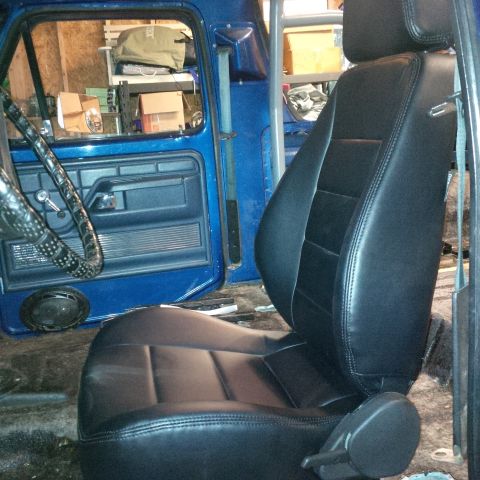 1978 Ford Bronco - The interior of a blue truck shows new black bucket seats and a roll cage installed.