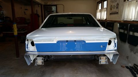 1991 Ford LTD Crown Victoria - Rear view of a white and blue car undergoing repairs in a garage, missing its taillights and bumper.