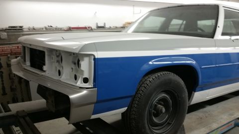 1991 Ford LTD Crown Victoria - This Ford Crown Victoria is in a body shop, missing its grille and headlights, with a two-tone paint job.