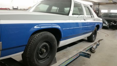 1991 Ford LTD Crown Victoria - A two-tone blue and grey 1991 Ford Crown Victoria LTD sedan is positioned on a vehicle lift in a garage.