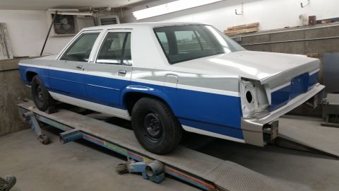 1991 Ford LTD Crown Victoria - This two-tone sedan, possibly a Ford Crown Victoria, is shown on a lift in a workshop setting.