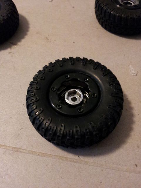 1995 Ford Bronco - Close-up of an off-road tire and wheel assembly, showing the tread pattern and a hex nut in the center.