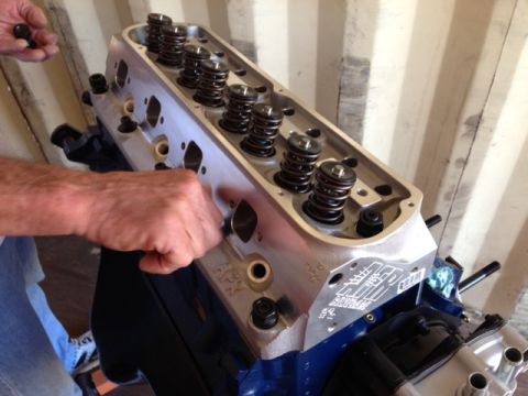 1996 Ford Bronco - A mechanic works on an engine cylinder head, showing the intricate valve and spring assembly.
