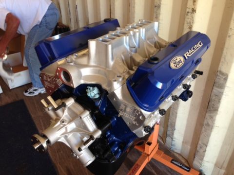 1996 Ford Bronco - A blue Ford Racing engine is mounted on an orange stand, with a person in the background.