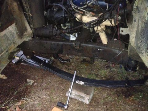 1971 Ford F-250 - The engine bay and front suspension of a vehicle are visible, with a leaf spring removed.