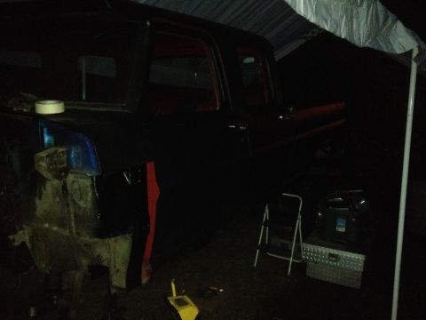 1971 Ford F-250 - A dark-colored 1971 Ford F-250 truck is parked under a tarp, appearing to be in a state of repair.