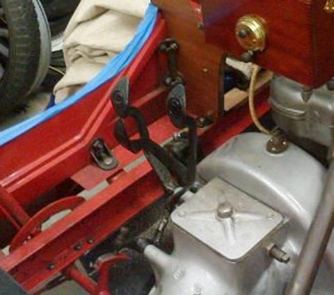 1909 Ford Model T - Interior view of a vintage vehicle's chassis, pedals, and engine components, with a wooden dashboard visible.