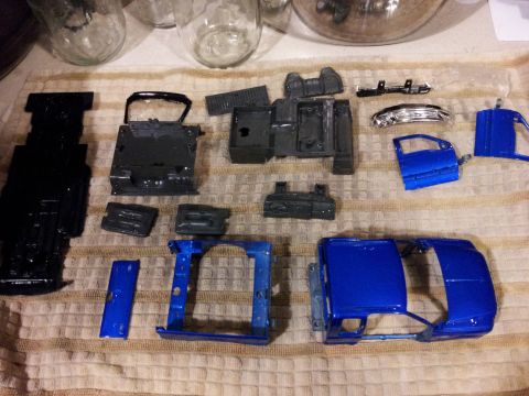 1995 Ford Bronco - Model car parts, including the body and chassis, are arranged on a cloth surface, some painted blue and others black.