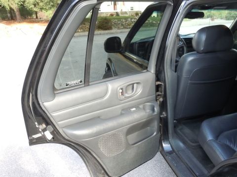 2001 Ford Crown Victoria - View of the interior door panel and rear seats of a black SUV with the rear door open.