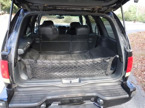 2001 Ford Crown Victoria - The rear cargo area of a black SUV is shown with a cargo net and folded seats.