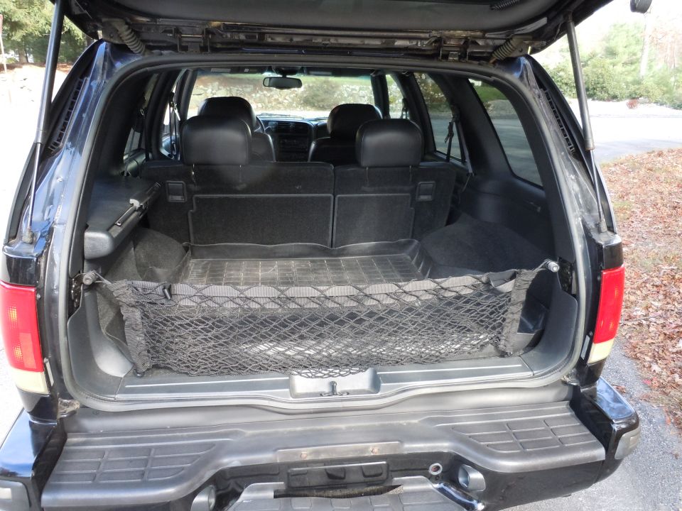 Rear cargo area of black SUV with cargo net and folded seats