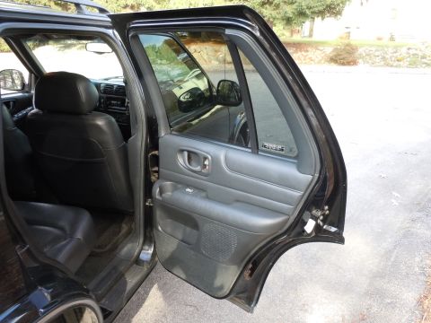 2001 Ford Crown Victoria - Interior view of a black SUV, showing the rear seats and the open rear passenger door.