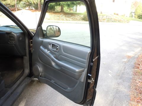 2001 Ford Crown Victoria - The interior of a black vehicle is visible with the driver's door ajar, revealing the door panel and dashboard.