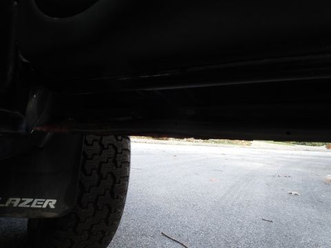 2001 Ford Crown Victoria - Close-up of a vehicle's undercarriage, revealing rust and a tire with 'BLAZER' branding.