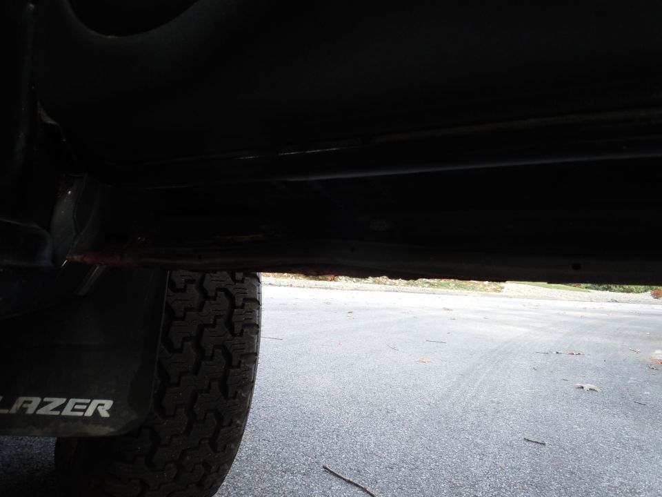 Undercarriage view showing rust on the frame rail and a tire with 'BLAZER' text on the mud flap