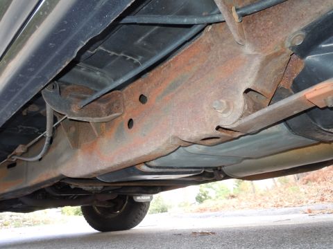 2001 Ford Crown Victoria - The underbody of this vehicle shows significant rust on the frame and suspension components, with 'Blazer' text visible on the tire.