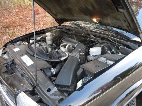 2001 Ford Crown Victoria - The engine bay of a black vehicle is visible with the hood raised, revealing various mechanical parts.