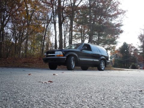 2001 Ford Crown Victoria - Black 2001 Chevrolet Blazer parked on a road during autumn.