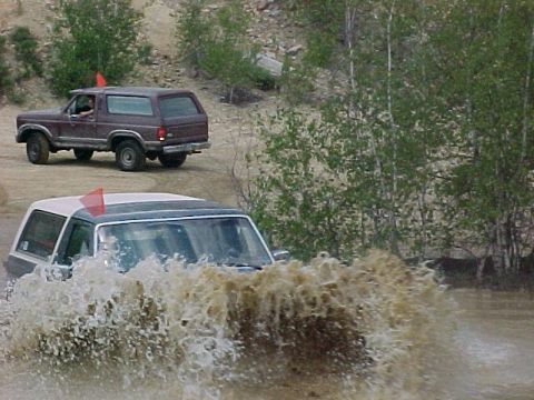 1993 Ford Bronco - Two Ford Broncos navigate a water crossing off-road.
