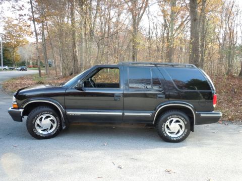 2001 Ford Crown Victoria - Side view of a black SUV, identified as a Blazer by the badging on its lower body trim.