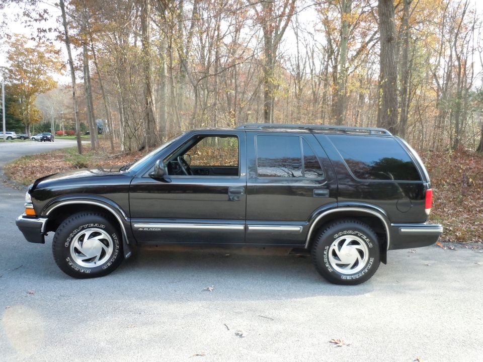 Black SUV side view. "BLAZER" text visible on lower body trim