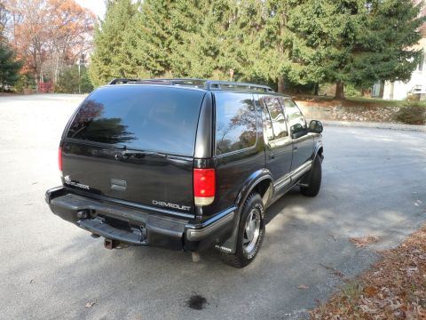 2001 Ford Crown Victoria - A black Chevrolet Blazer SUV is parked outdoors on an asphalt surface with trees in the background.