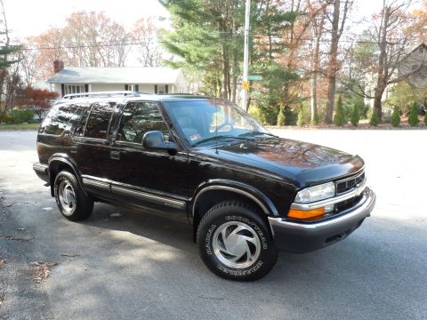 2001 Ford Crown Victoria - Black Chevrolet Blazer parked on a street in front of a house.