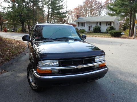 2001 Ford Crown Victoria - This black SUV, likely a 1998 model based on its grille, is parked on a residential street.