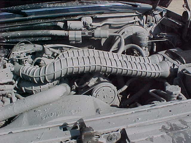 Truck engine bay caked in dried mud after off-roading, viewed from above