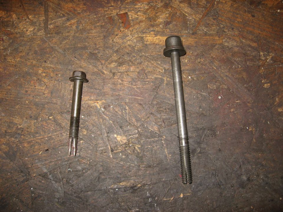 Two bolts on a wooden surface. One is shorter with a hex head and threaded end. The other is longer with a cap-like head and threaded end
