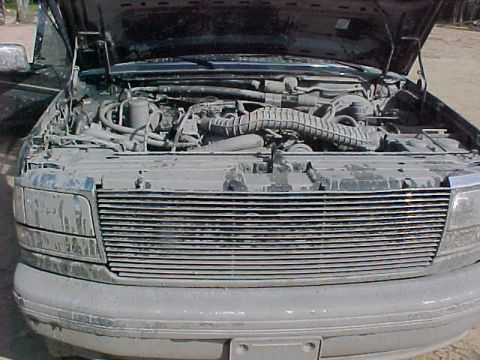 1993 Ford Bronco - The front grille and dusty engine of a 1992 Ford Bronco are visible with the hood up.
