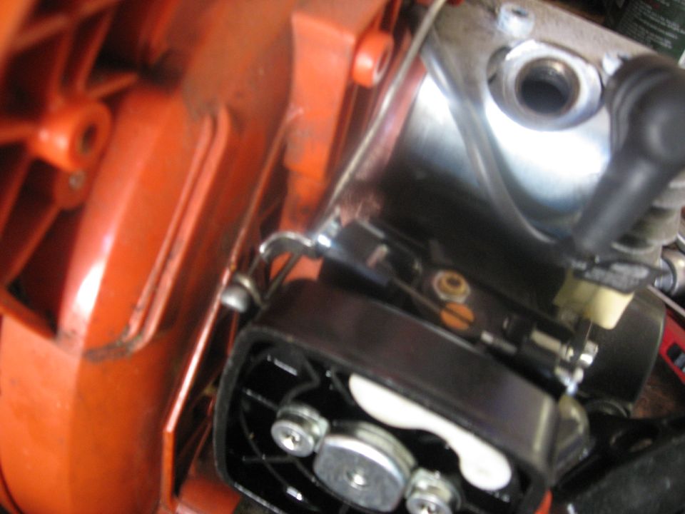 Close-up of a chainsaw's internal engine components, showing the carburetor area and orange casing