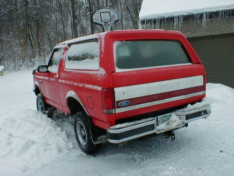 1990 Ford Bronco - Red 1990 Ford Bronco covered in snow with a basketball hoop in the background.