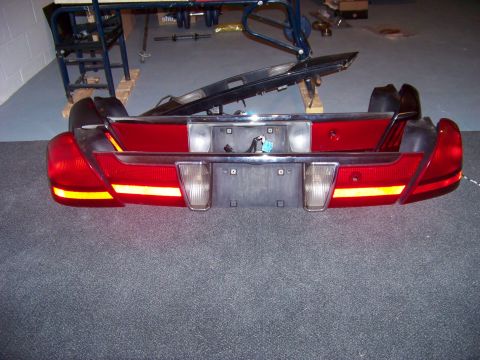 1999 Mercury Grand Marquis - Rear bumper and tail light assembly for a car is shown in a workshop setting.