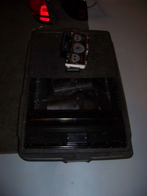 1999 Mercury Grand Marquis - A car's instrument cluster is placed on a black storage container, with a red taillight in the background.
